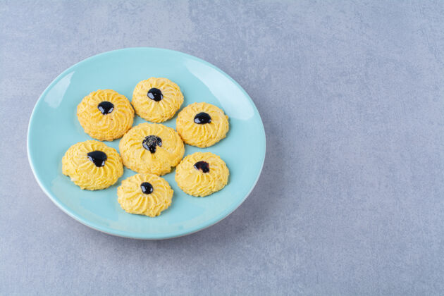 招待一些美味的黄色饼干和巧克力糖浆放在蓝色盘子里面团饼干面包房