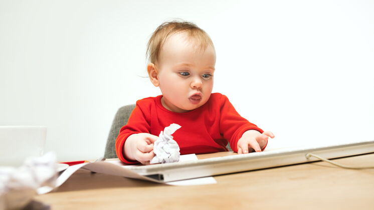 教育快乐的小女婴坐在一个白色的工作室里 用现代电脑或笔记本电脑的键盘婴儿可爱健康