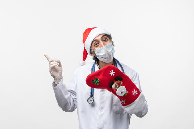 圣诞节正面图男医生拿着大红袜在白墙上病毒冠状病毒-假日冠状病毒肖像病毒