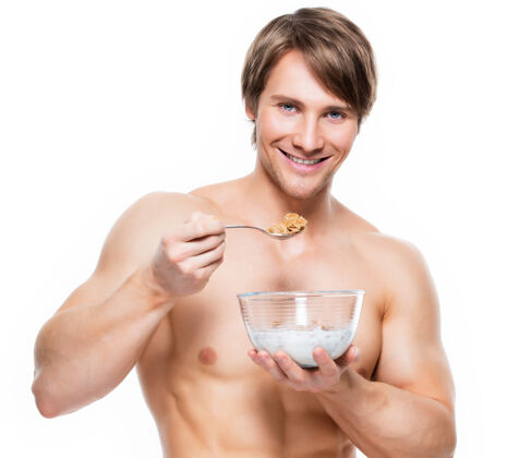 男性一个年轻迷人的肌肉男吃牛奶片的肖像-隔离在白墙上饮食人胡茬
