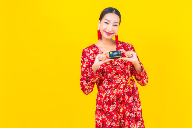 休闲肖像美丽的亚洲年轻女子信用卡购物黄色隔离墙购物者付款购物