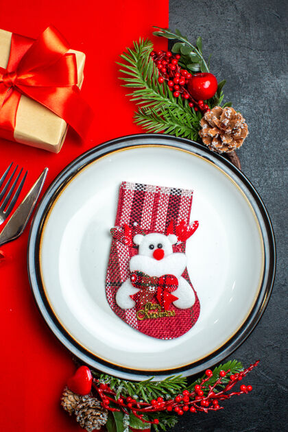晚餐新年背景的垂直视图与xsmas袜子上的餐盘餐具套装装饰配件杉木树枝旁边的礼物上的红色餐巾晚餐盘子圣诞冷杉