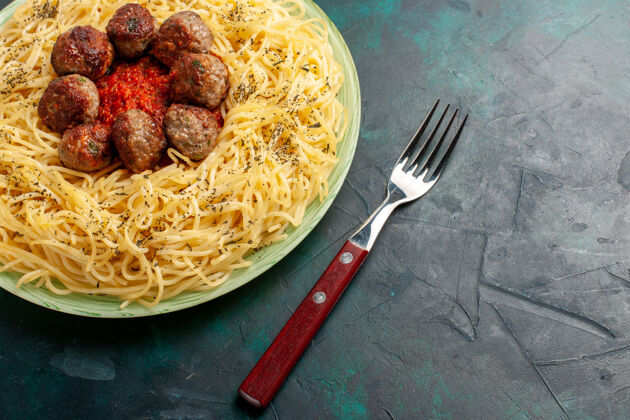 晚餐顶部近距离观看美味的意大利面食与肉丸和番茄酱在深蓝色的表面美味烹饪面食