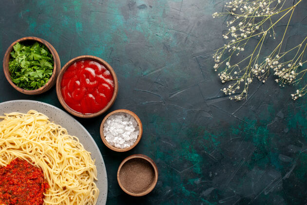 晚餐顶视图煮熟的意大利面食与肉和不同的调味品在深蓝色的表面面团烹饪硬币