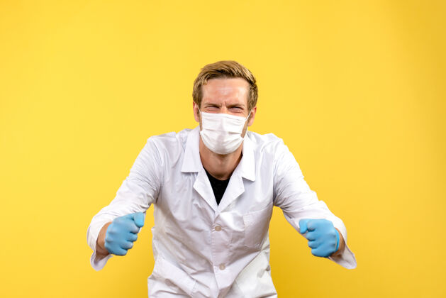 实验室正面图黄色背景上戴着口罩的男医生欢呼雀跃大流行冠状病毒-健康病毒冠状病毒视图肖像