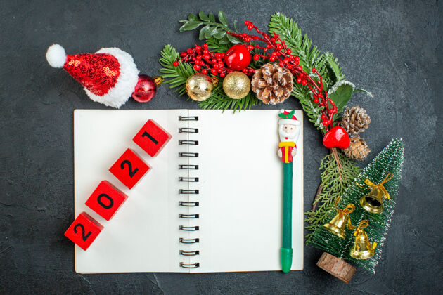 顶部顶视图的圣诞心情与杉木树枝圣诞老人帽子圣诞树上的笔记本数字在黑暗的背景浆果笔记本树枝