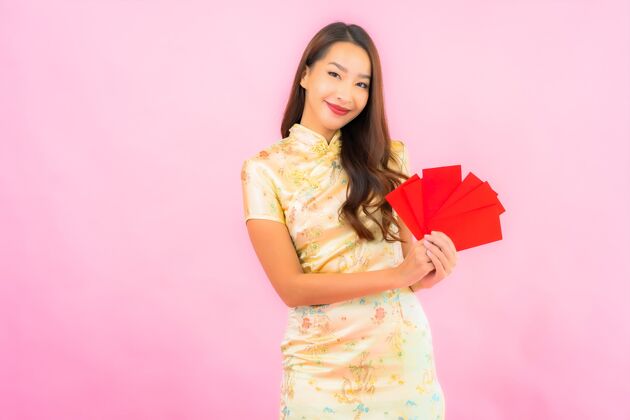 漂亮在粉红色的墙上画一幅美丽的亚洲年轻女子拿着红包微笑女孩愿望