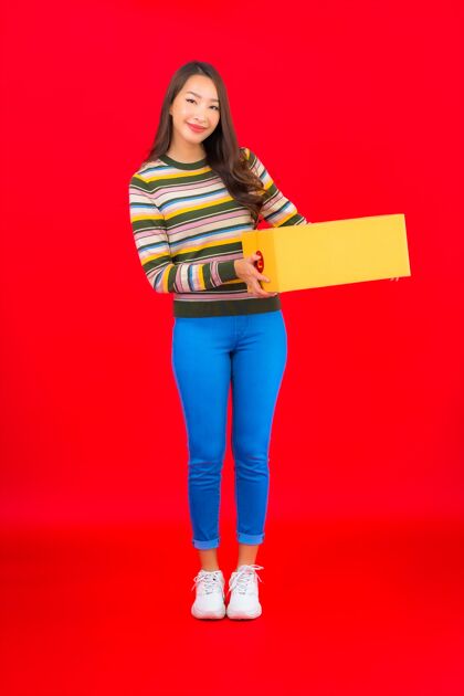 携带在红色的隔离墙上画一幅美丽的亚洲年轻女子拿着包裹盒发送纸板邮政