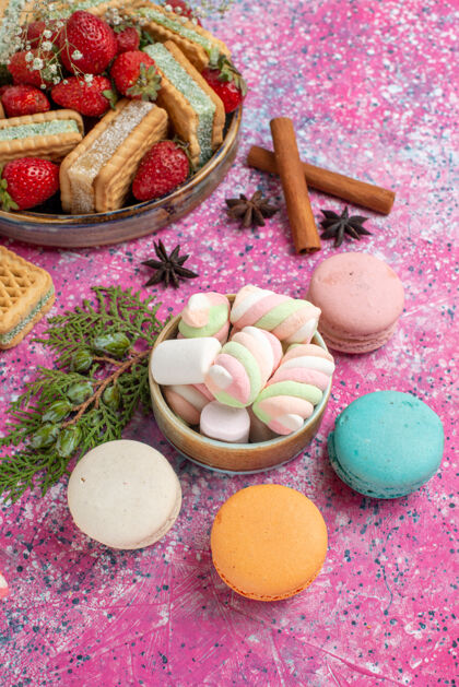 糖果半俯瞰美味的华夫饼干与马卡龙和新鲜的红色草莓粉红表面麦卡龙饼干蔬菜