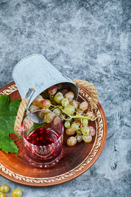 盘子一桶葡萄和一杯果汁放在大理石上玻璃葡萄饮料