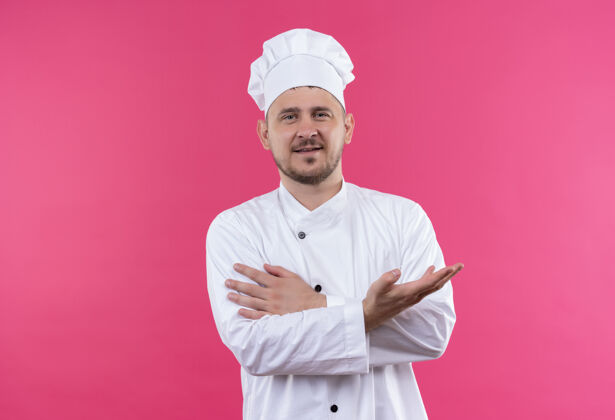 帅气年轻帅气的厨师身着厨师制服 手空空的 手放在手臂上 在粉色的空间里与世隔绝厨师高兴手
