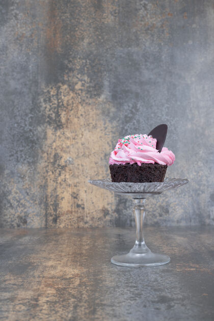 洒点粉色奶油蛋糕放在大理石表面的玻璃板上玻璃美味美味