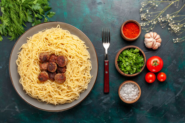 晚餐俯视图煮熟的意大利面食 深蓝色表面有肉丸和绿色餐厅食物菜肴