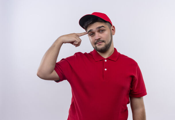 帽子身穿红色制服 头戴鸭舌帽的年轻送货员自信地指着自己的太阳穴专注于任务年轻立场传递