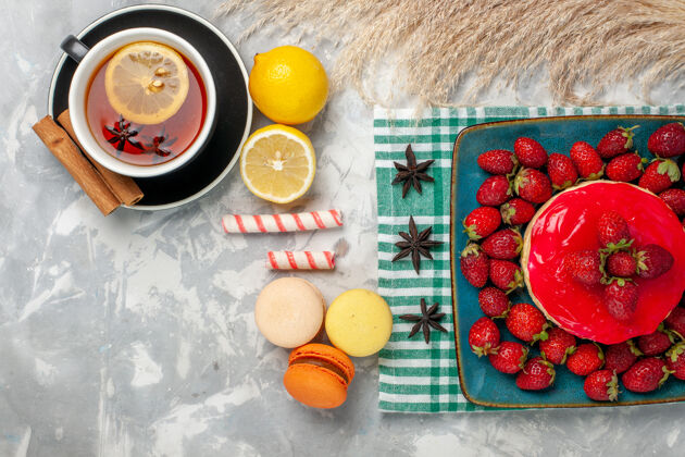 茶俯瞰美味的草莓蛋糕与新鲜草莓一杯茶和麦卡龙在白色的桌子上草莓早餐草莓