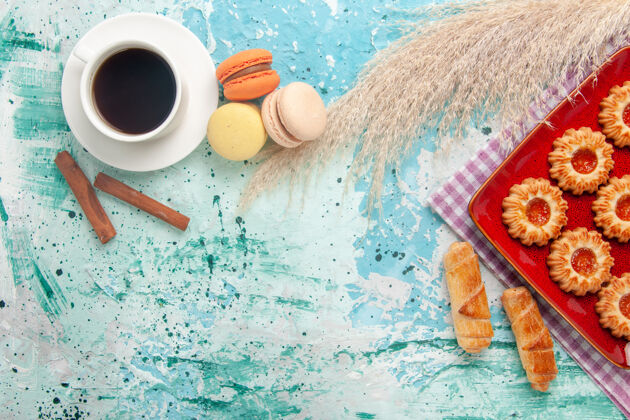 派顶视图甜饼干与百吉饼马卡龙和茶杯浅蓝色背景水蛋糕涂抹器