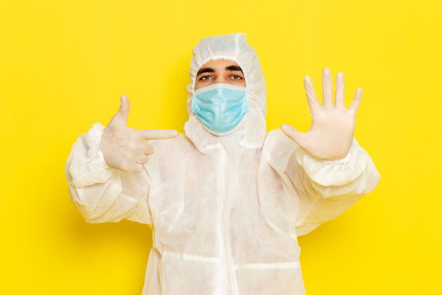 科学身穿特殊防护服 戴着面罩的男性科学工作者的正面图 手掌放在淡黄色的墙上正面肖像服装