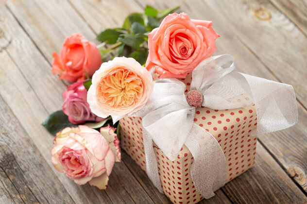 节日包装精美的礼物和一束玫瑰放在一张模糊不清的木桌上玫瑰花束新鲜