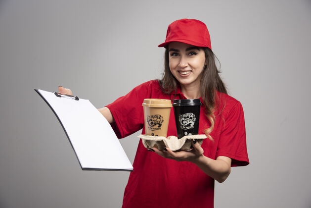 职业送货员拿着咖啡杯和剪贴板女人送货饮料
