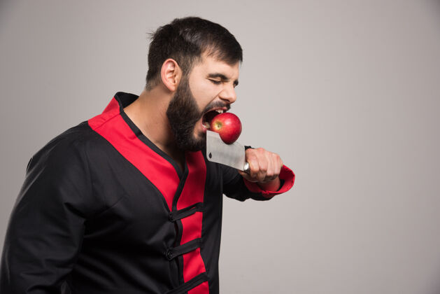 水果有胡子的男人在刀上咬红苹果开模型美味