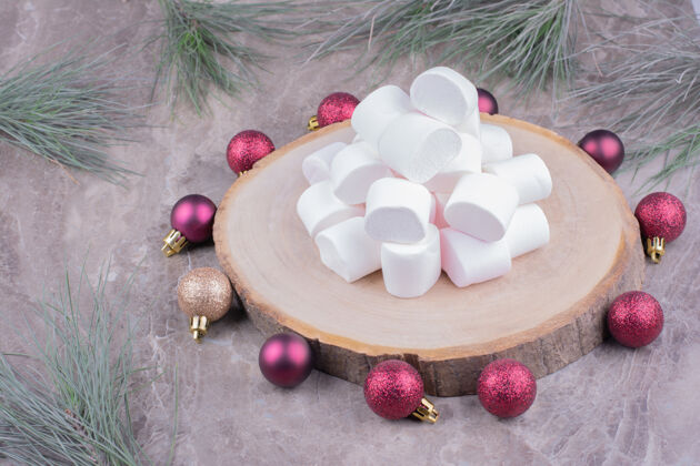 甜点白色的棉花糖放在木制的盘子里 周围是红色的圣诞球面包房厨房糕点