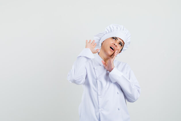烹饪身穿白色制服的女厨师手拉着嘴 神情好奇举行厨房工作