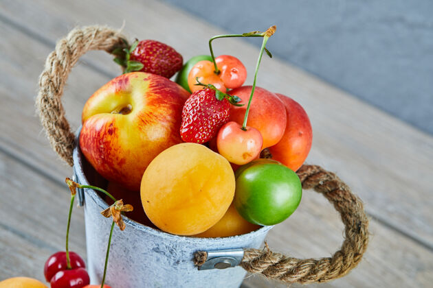 自然木桌上放着一桶夏天的新鲜水果水果盘子餐桌