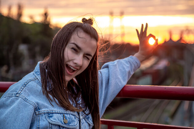 桥一个年轻女子在桥上 在美丽的日落前摆姿势欢呼姿势太阳