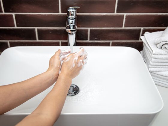 护理在自来水下用肥皂水洗手个人卫生和健康的概念手妇女泡沫