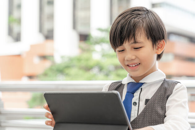 学生小男孩用智能手机平板电脑上商业区 教育理念经理电话科技