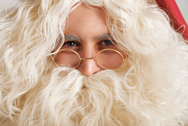 胡须可爱的圣诞老人 灰蓝色的眼睛和金色的眼镜 特写肖像积极圣诞老人帽子