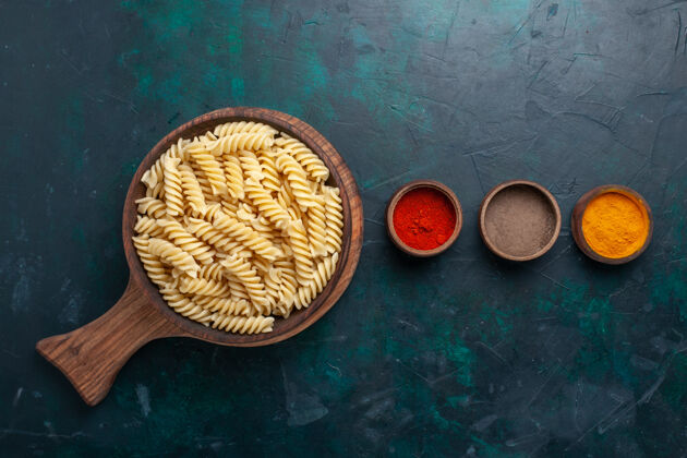 调味品在深蓝色的桌子上可以俯瞰意大利面食和调味品木制软体动物桌子