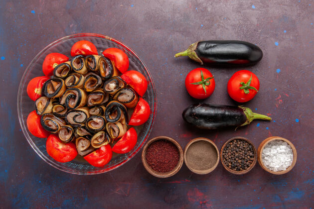 打击乐顶视图蔬菜餐-在黑暗的地板上用茄子和调味料切成薄片和卷成卷的西红柿西红柿豆子烹饪