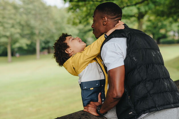 男孩一个非洲裔美国小孩和他的父亲在公园里玩孩子爱拥抱