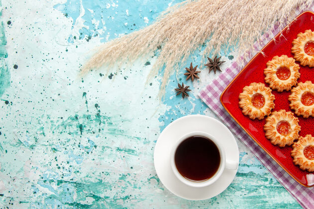 盘子顶视图糖饼干内的红色盘子上有一杯茶的蓝色背景早餐咖啡茶碟