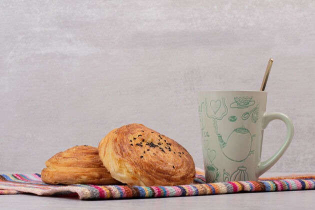 面包房两杯护目镜和一杯茶放在桌布上甜点汤匙传统