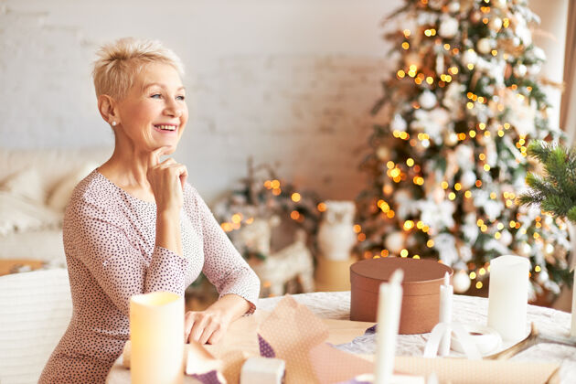 节日情绪化迷人的退休女性 披着精灵的发型 享受着圣诞节的准备 用手工纸包着礼物 有着喜出望外的表情 给家人和朋友做礼物圣诞节惊喜女人