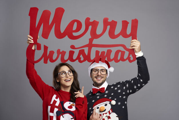 圣诞毛衣一对夫妇举着一个大牌子 上面写着圣诞快乐成人好玩快乐