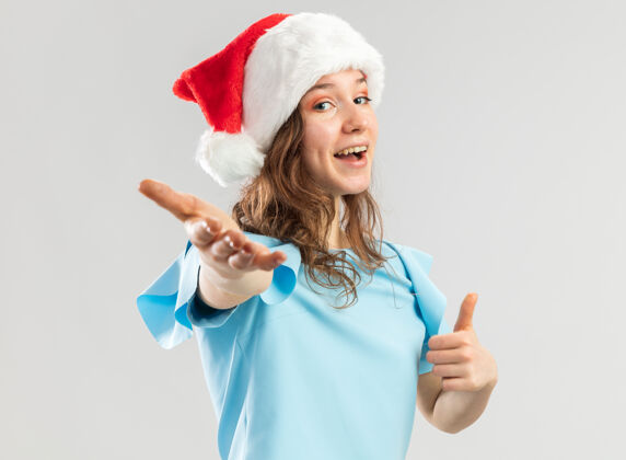 女人穿着蓝色上衣 戴着圣诞帽的年轻女子 看上去很开心 很积极 用手做了一个过来的手势蓝色新来