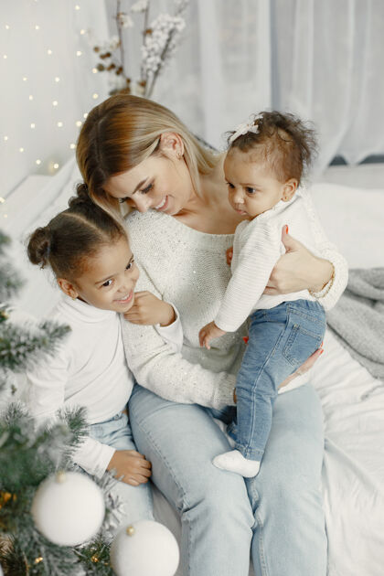 女儿人们在为圣诞节做准备母亲在和女儿们玩耍一家人在节日的房间里休息孩子穿着毛衣圣诞节女装饰