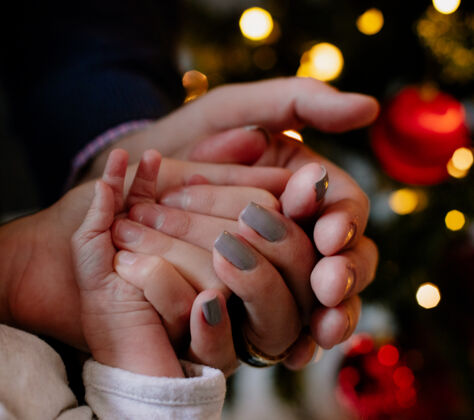 家近距离看爸爸妈妈和他们的孩子一起在家里的手在圣诞节期间围绕圣诞树母亲手圣诞树