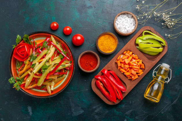 油顶视图切片甜椒不同颜色的蔬菜沙拉与原料和油在深蓝色的背景深色午餐晚餐