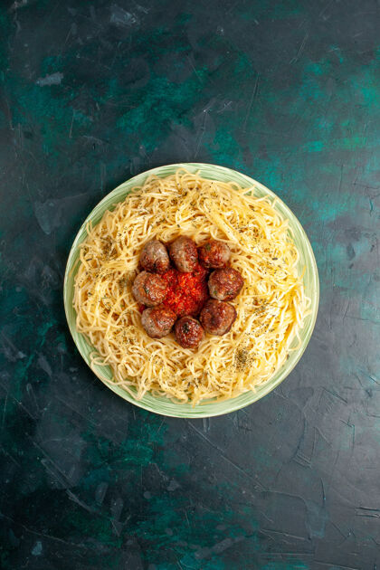 面食在深蓝色背景上俯瞰美味的意大利面食和肉丸背景餐菜