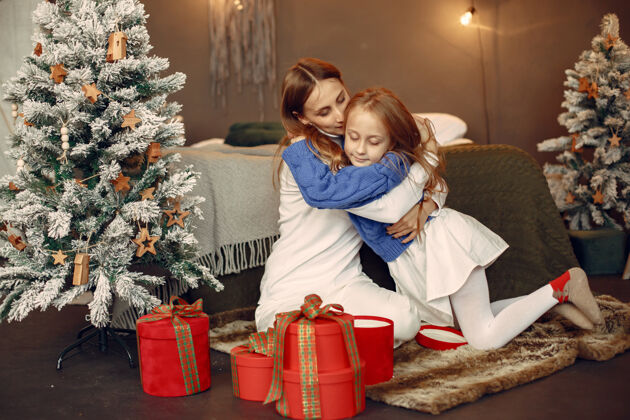 蓝色人们在为圣诞节做准备母亲在和女儿玩耍一家人在节日的房间里休息孩子穿着蓝色毛衣面纱闪亮坐