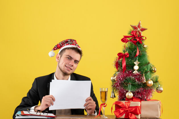 男工人正面图男性工人坐在他工作的地方后面拿着黄色的文件人圣诞节工作