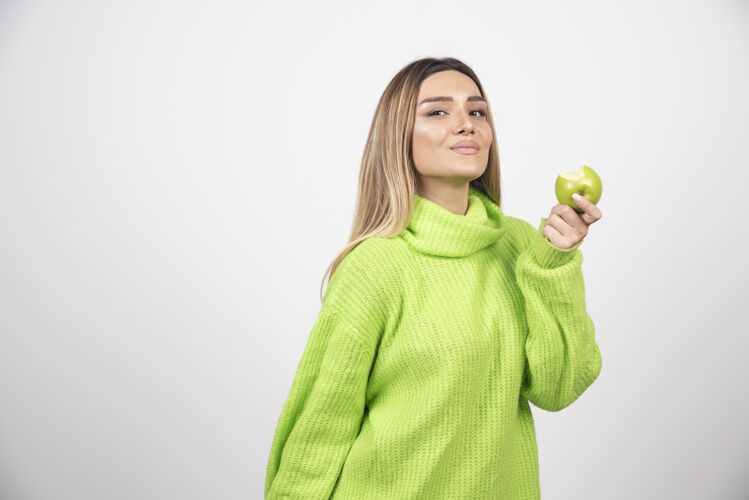 年轻穿着绿色t恤的年轻女子手里拿着一个苹果女性保持水果
