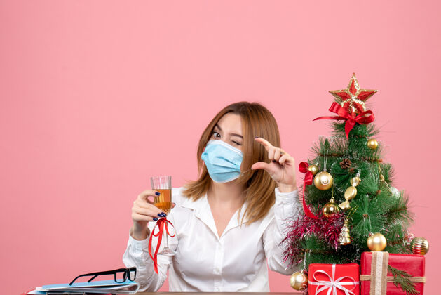 圣诞节戴着无菌口罩的女工的正面图 庆祝圣诞节 粉红色的香槟工人面具粉色