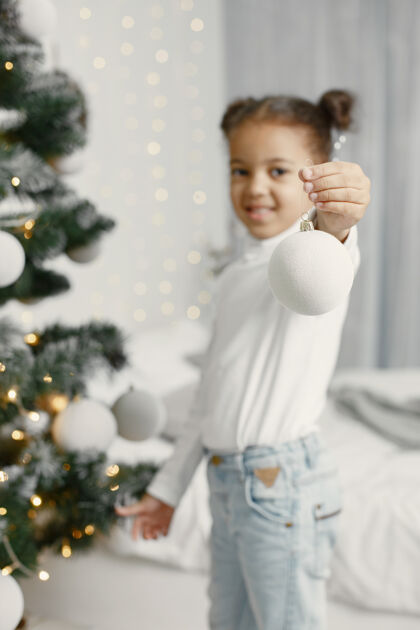礼物穿白色毛衣的孩子站在圣诞树旁的女儿圣诞树人美国