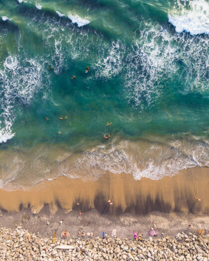岩石人们游泳和坐在瓦尔卡拉海滩的俯视照片岩石热带游泳