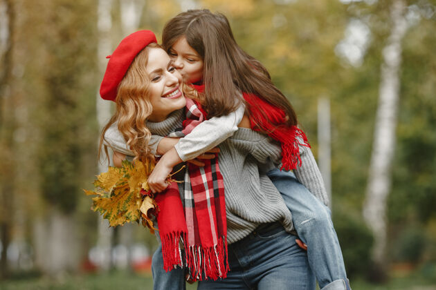 玩耍时髦的母亲带着女儿黄色的秋天戴着红领巾的女人休闲围巾肖像